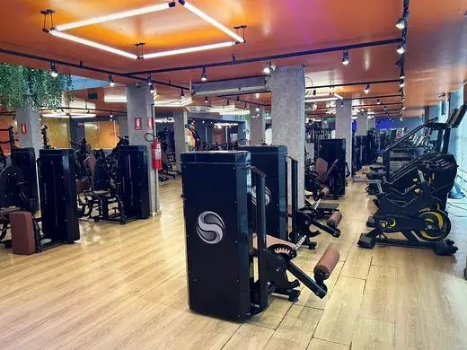 Bicicletas ergométricas e de spinning alinhadas ao lado das estações de musculação.