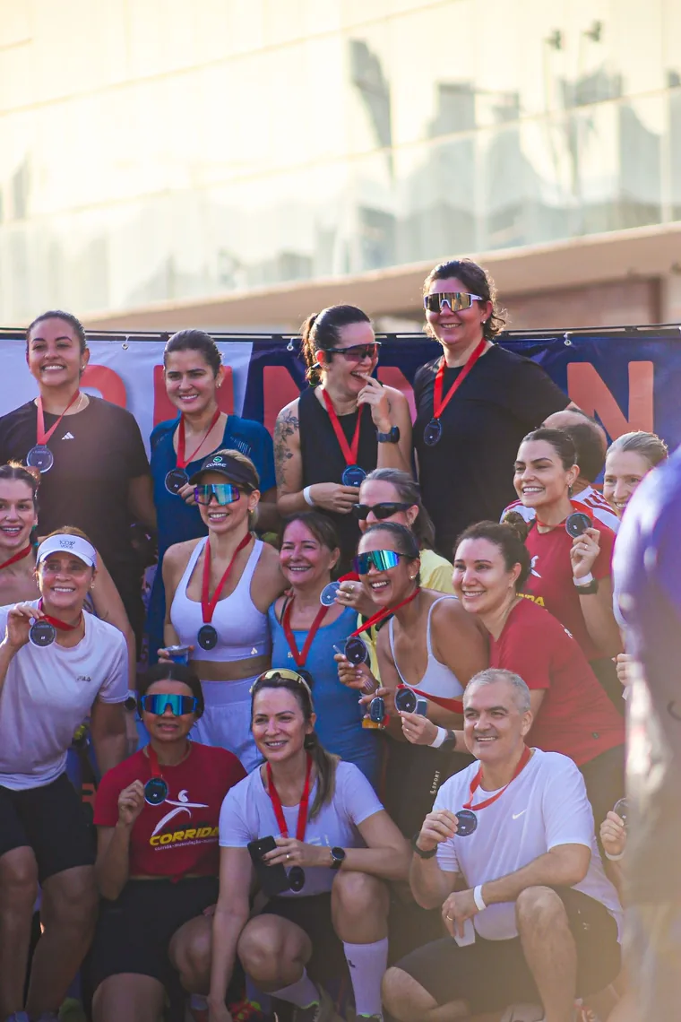 Corredoras e corredores do clube sorrindo com as medalhas da prova na mão.