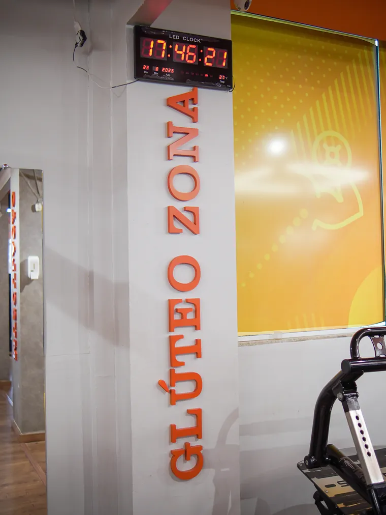 Coluna com as letras Glúteo Zona em pé e um relógio digital de LED no alto, marcando 17:46.