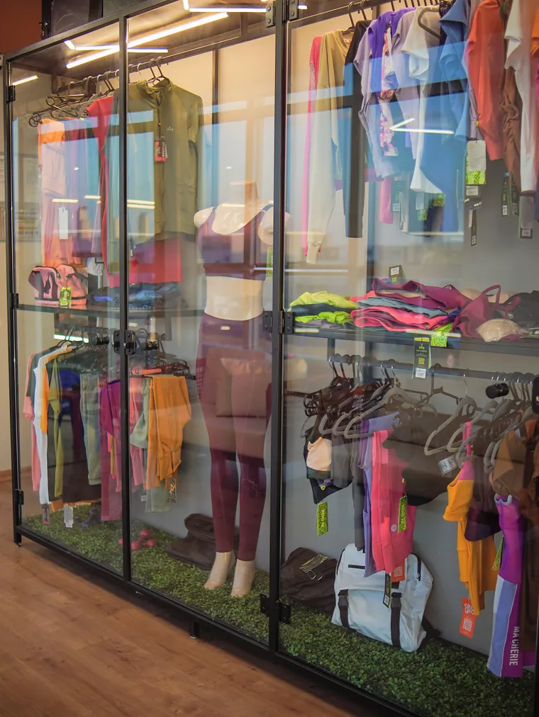 Vitrine de vidro com roupas de treino femininas penduradas e expostas em manequins.