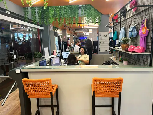 Balcão da recepção com atendente e banquetas.